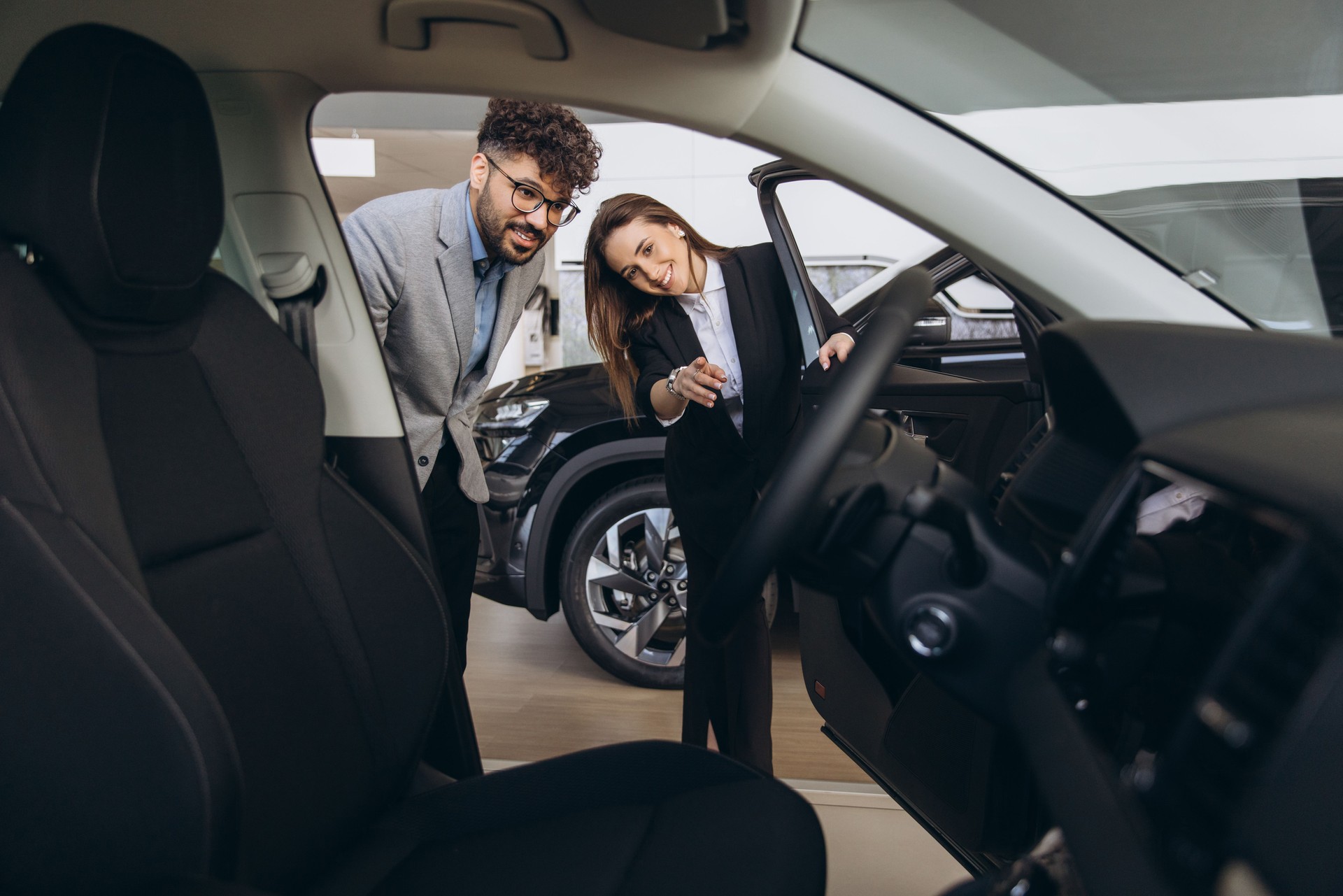 Car dealer showing new vehicle to customer in car dealership